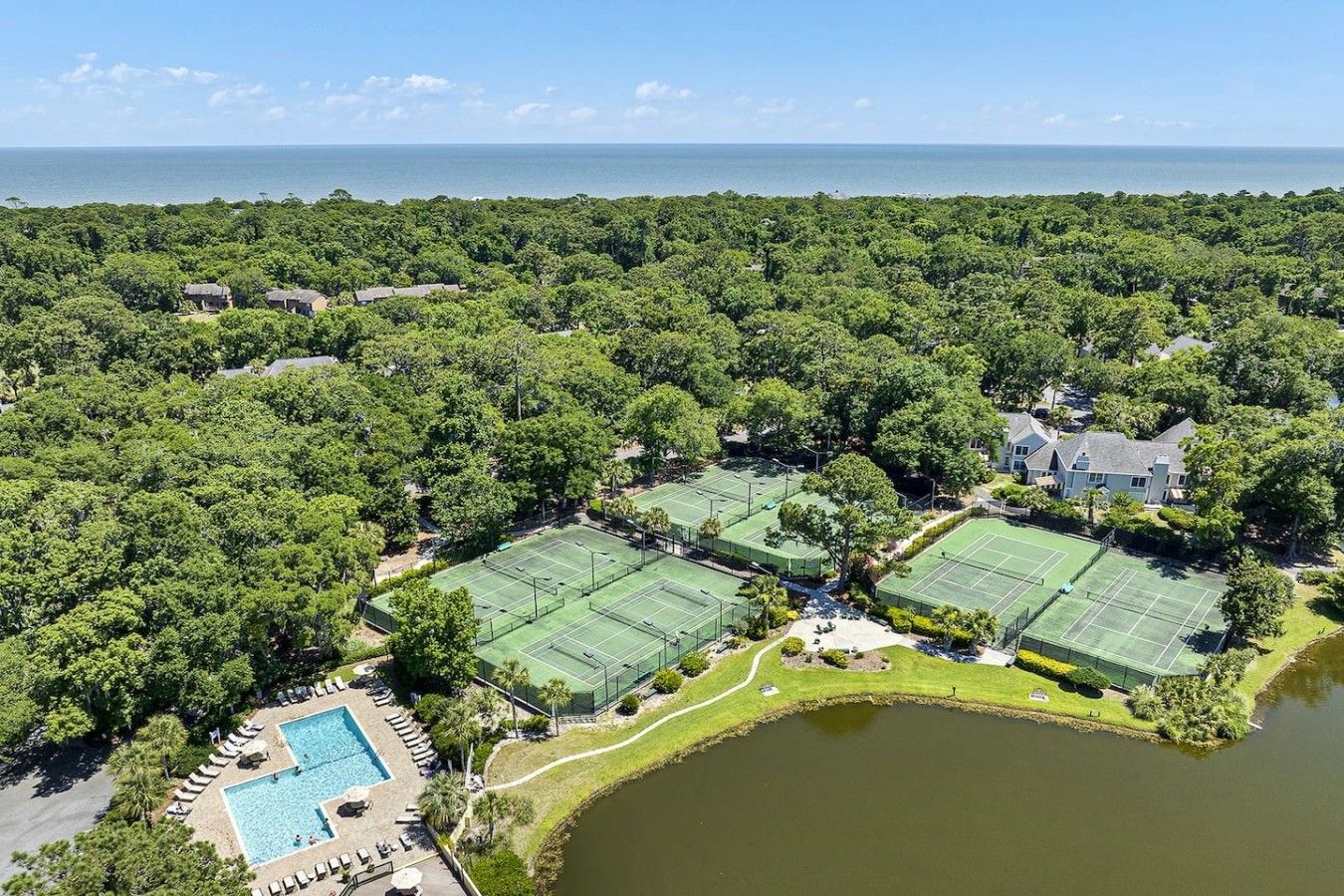 A large estate with multiple tennis courts, a swimming pool, and a lake.