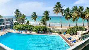 A swimming pool with blue water, surrounded by palm trees and a beach view. - Brisa Oceanfront + Beach + Pool + Ocean View Balcony (San Juan)