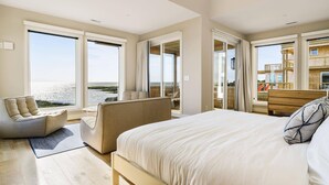Ein modernes Schlafzimmer mit einem großen Bett, einer Couch und Meerblick.