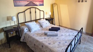 A bedroom with a bed, bedside tables, a nightstand, a mirror, and a painting on the wall. - Penthouse Casa Orymar El Cotillo (El Cotillo)