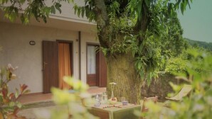 Ein gemütlicher Sitzbereich im Freien mit einem Tisch für zwei Personen, umgeben von üppigem Grün und einem großen Baum.