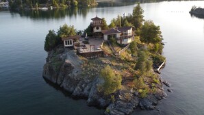 A lakeside property with a main house and a separate tower, surrounded by trees and rocky terrain. - PRIVATE ISLAND RETREAT On Gorgeous Flathead Lake Montana!!! (Somers)