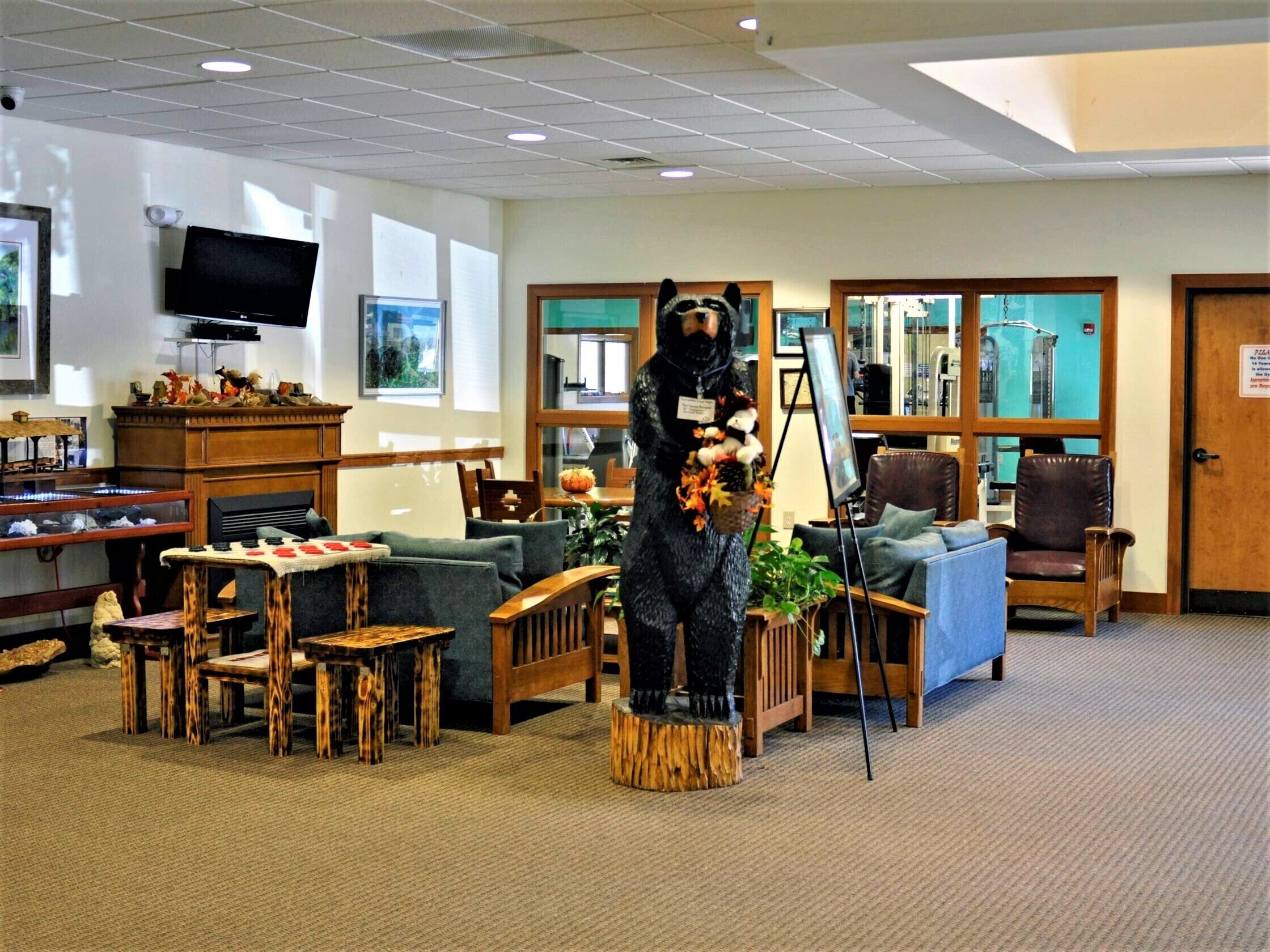 A cozy lobby with a large bear statue, comfortable seating, a television, and a reception desk.