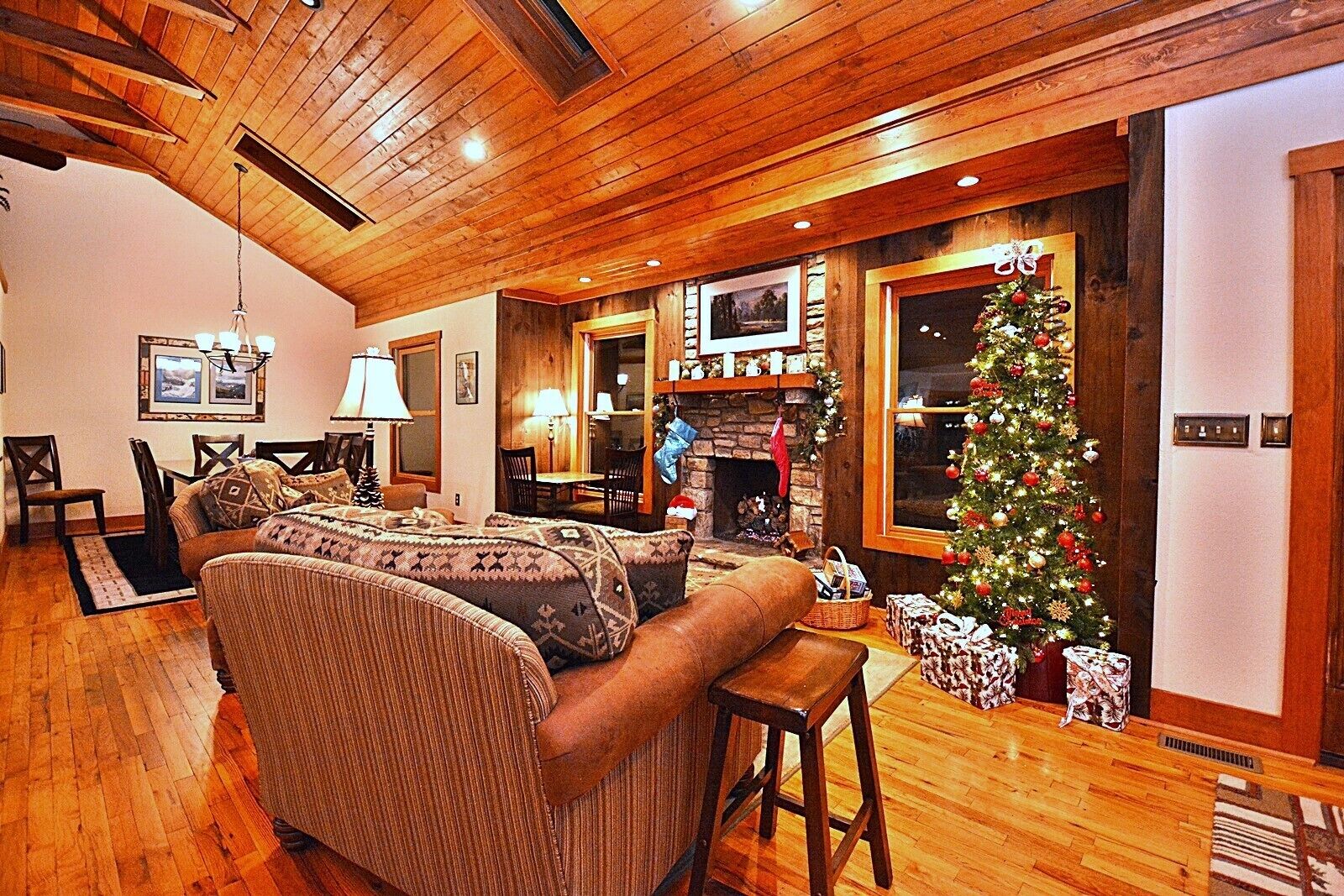 Una sala de estar acogedora con chimenea, techo de madera y un árbol de Navidad decorado.