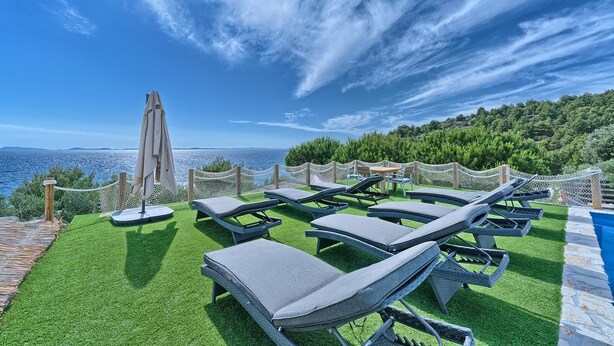 A rooftop terrace with lounge chairs, a table, and a pool, overlooking a scenic coastline. - Beachfront Villa New Horizons II (Murter)