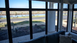 A room with large windows overlooking a lake and a road. - Nautilus in The Point (Point Lonsdale)