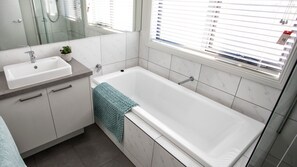 Une salle de bain moderne avec un lavabo blanc, un miroir et une baignoire.