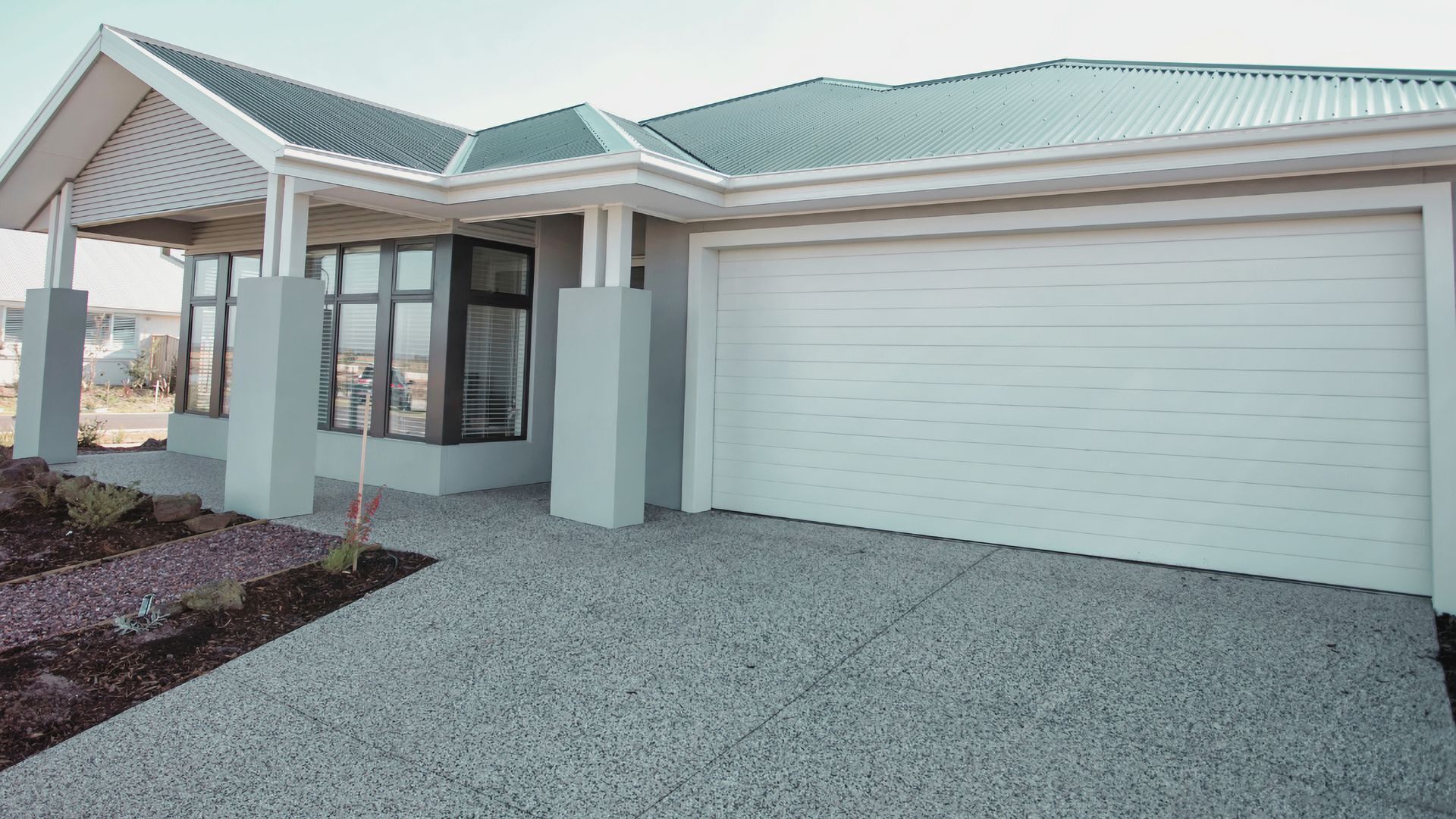 A modern house with a garage, a covered porch, and a landscaped front yard.