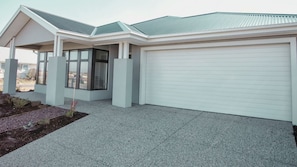 A modern house with a garage, a covered porch, and a landscaped front yard.