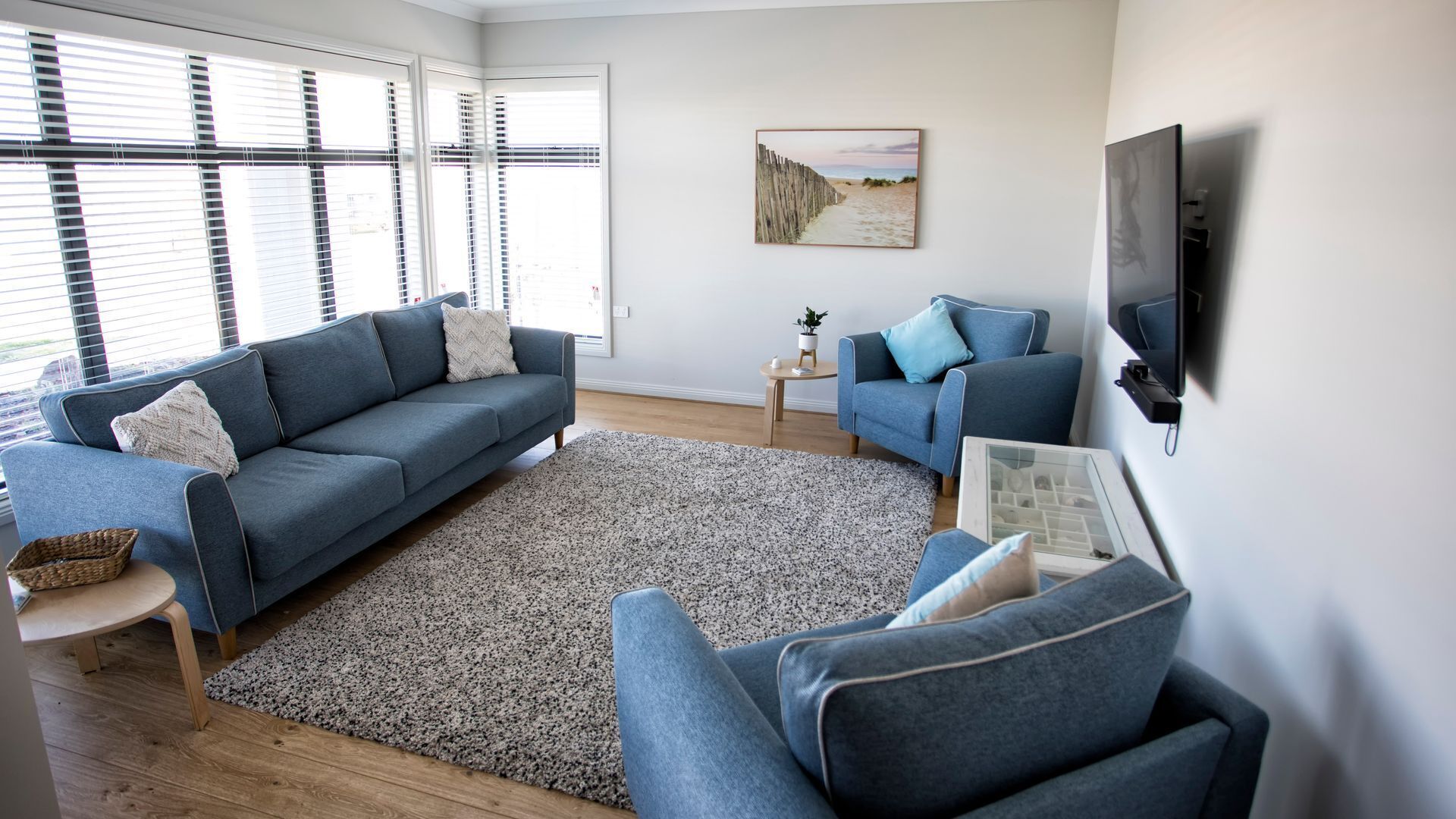Een moderne woonkamer met een bank, fauteuil en een kleine tafel met een plant.