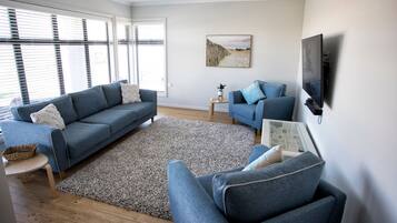 Een moderne woonkamer met een bank, fauteuil en een kleine tafel met een plant.
