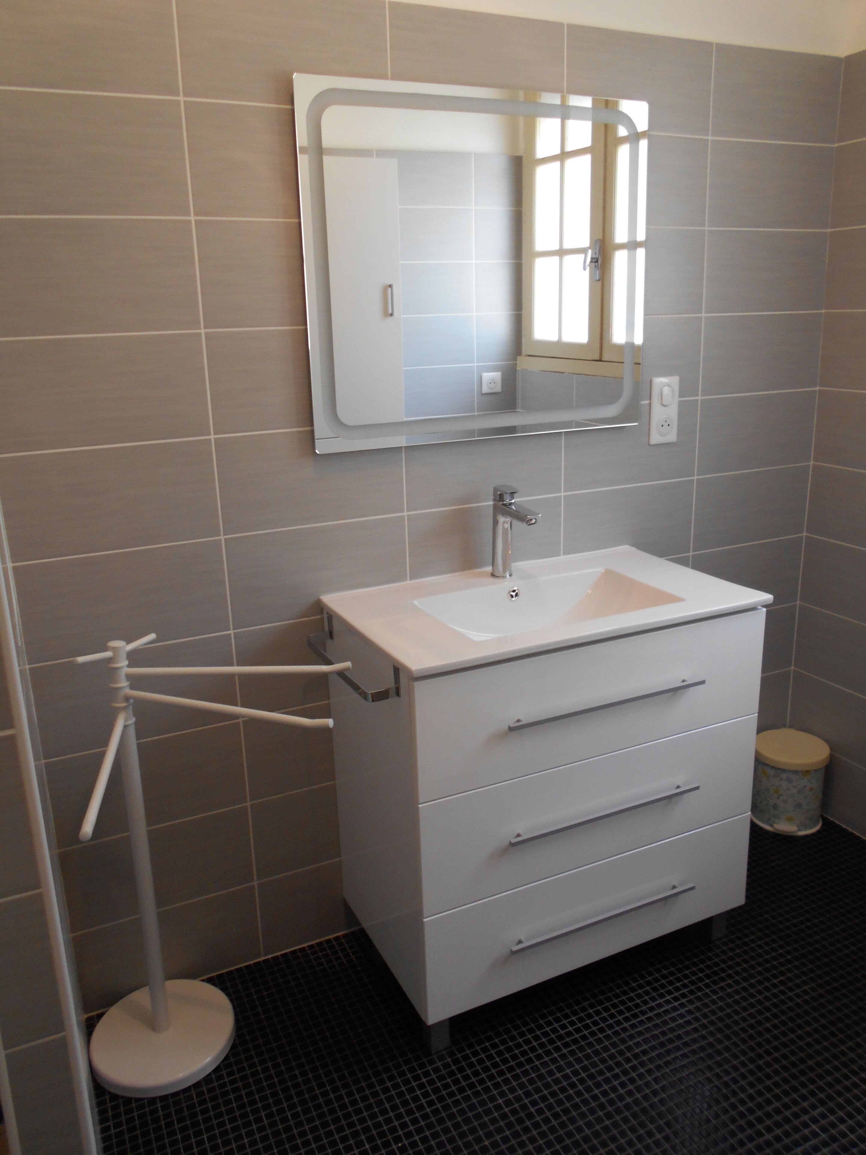 A bathroom with a white sink, a mirror above it, and a toilet with a lid.
