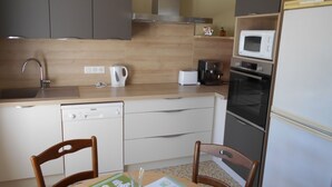 A compact kitchen with a sink, a coffee maker, a microwave, and a refrigerator. - Gîte Le Penten (Villeréal)