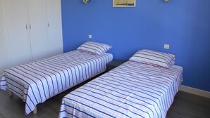 A room with two single beds, a wardrobe, and a painting on the wall. - Gîte Le Penten (Villeréal)