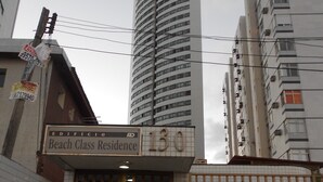 Un immeuble sur lequel on peut lire l’inscription « Résidence Beach Class » et où le numéro « 130 » est affiché au-dessus de l’entrée.