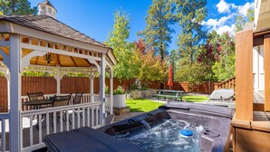 A hot tub in a backyard with a wooden deck, a gazebo, and a picnic table. - Separation Canyon Retreat (Flagstaff)