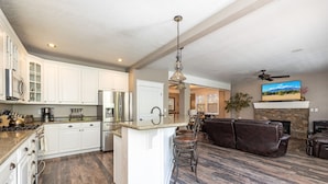 A modern kitchen with white cabinets, stainless steel appliances, and a central island with bar stools. - Separation Canyon Retreat (Flagstaff)