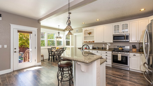 A spacious kitchen with white cabinetry, a central island, and a large stainless steel refrigerator. - Separation Canyon Retreat (Flagstaff)
