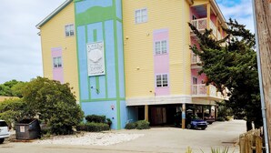 A multi-story building with a colorful facade, a covered parking area, and a visible entrance. - Across the street from the beach and a block from Mainstreet (North Myrtle Beach)
