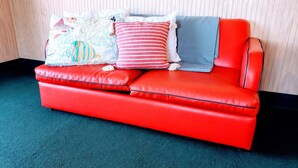 A red leather sofa with three pillows against a striped wall. - Across the street from the beach and a block from Mainstreet (North Myrtle Beach)
