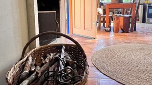 A rustic interior with a fireplace, a wooden table, and a wicker basket filled with logs. - Lots of charm and comfort in the mountains of Cunha (Cunha, Sp)