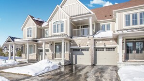 A large, multi-story house with a covered porch and a garage. - Executive Town Home - Historical Snowbridge Village, Mountain View Blue mountain (The Blue Mountains)
