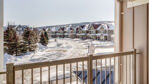 A balcony with a view of a snow-covered residential area with houses and trees. - Executive Town Home - Historical Snowbridge Village, Mountain View Blue mountain (The Blue Mountains)