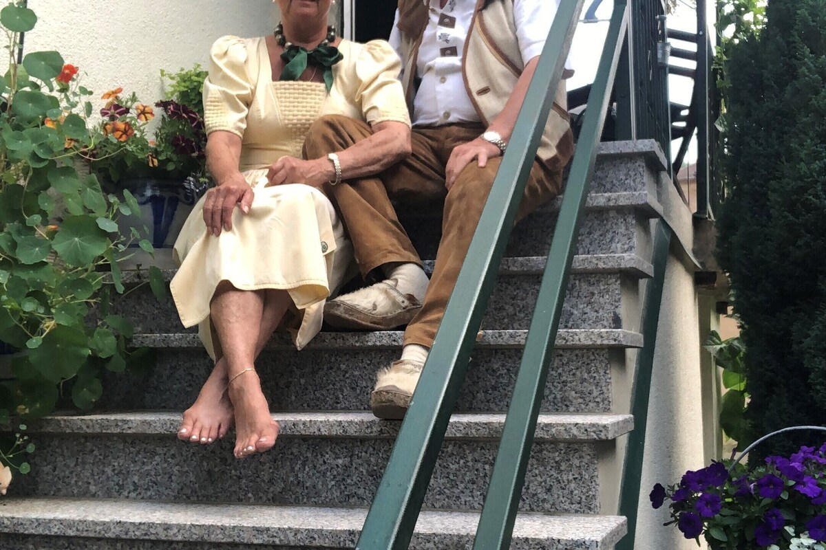 Two people sitting on outdoor stone steps with a house in the background.