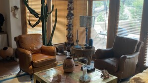 A cozy living room with leather sofas, a coffee table with decorative items, and a large cactus plant. - Spectacular Mountain Views, Supreme Tranquility & Privacy in Tesuque! (Santa Fe)