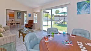 Amplia sala de estar con una mesa de comedor lista para una partida de póker, un sofá cómodo y vistas al jardín trasero.