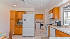 Una cocina moderna con armarios de madera, un refrigerador blanco, un microondas y un lavavajillas.