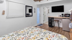 Une chambre avec un lit, un bureau, une chaise, une télévision et une salle de bain.