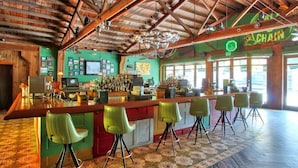 Un bar avec un plafond en bois, des chaises vertes et un sol à motifs.
