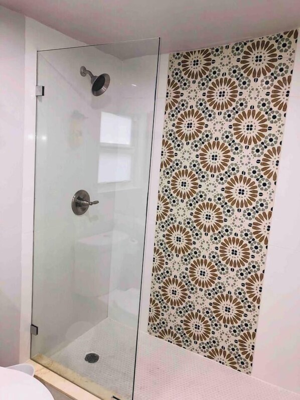 A shower enclosure with a glass door and a decorative tile wall.
