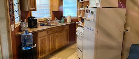 Una cocina compacta con armarios de madera, un refrigerador blanco, una estufa y un lavabo.