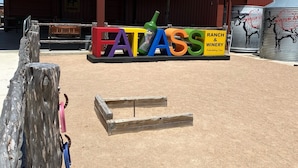 Placa para 'Fatass Ranch & Winery', com vista clara do edifício ao fundo.