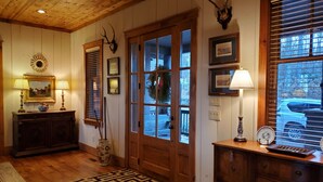 A wooden interior with a patterned rug, a wooden bench, a dresser, and a mirror.