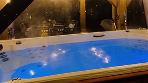 A hot tub with a view of the sky, surrounded by wooden beams and string lights.