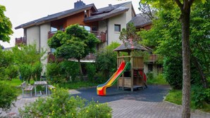 A children's playground with a slide, surrounded by a brick pathway and greenery. - Apartment Allmi by Interhome (Meiringen)