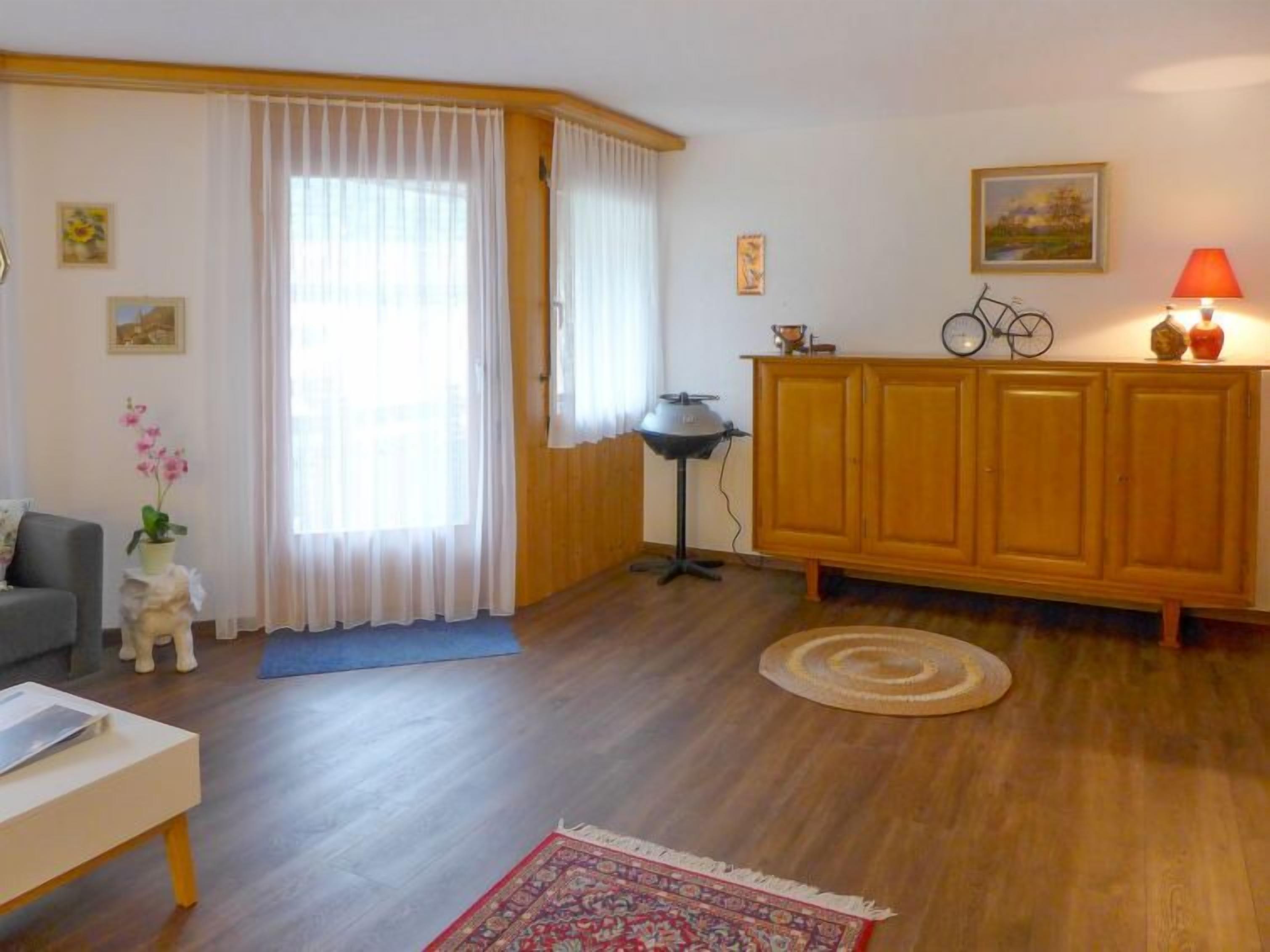 Un salon avec un plancher en bois, un canapé, une table basse, un meuble, une lampe et un tapis.