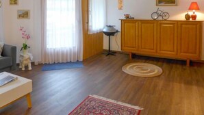 A living room with wooden flooring, a sofa, a coffee table, a cabinet, a lamp, and a rug. - Apartment Allmi by Interhome (Meiringen)