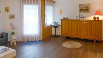 Un salon avec un plancher en bois, un canapé, une table basse, un meuble, une lampe et un tapis.