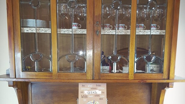 Um armário de madeira com portas de vidro, gavetas e uma placa.