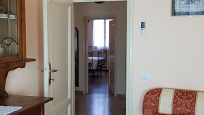 A living room with a wooden cabinet, a red patterned sofa, and a hallway leading to another room. - Functional and well-kept apartment: all perfectly kept. (Firenze)