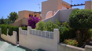 A modern villa with a pool, surrounded by lush greenery and vibrant flowers.