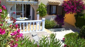 A Mediterranean-style building with a terrace, outdoor seating, and vibrant bougainvillea flowers.