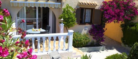 A Mediterranean-style building with a terrace, outdoor seating, and vibrant bougainvillea flowers.