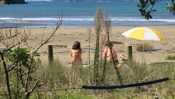 A beach scene with a woman in a yellow bikini and a person in a pink swimsuit. - Spacious house with optimal decks near popular  beaches (Warkworth)