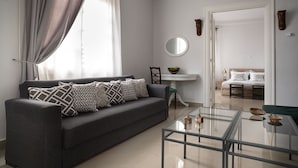 A modern living room with a grey sofa, a glass coffee table, and a white console table with a mirror. - Polytimon, an Athenian Neoclassical Apartment (Athens)