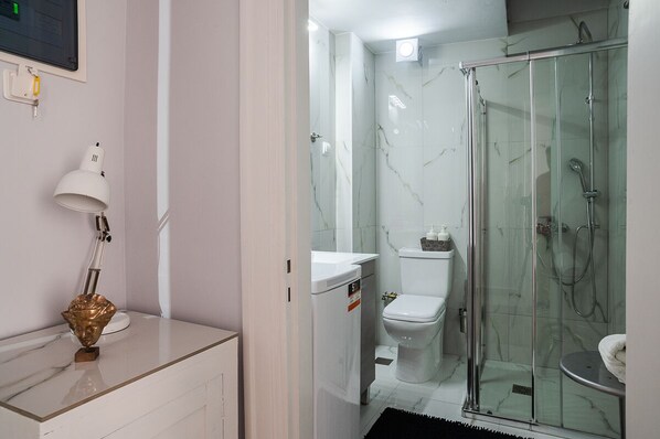 A modern bathroom with a glass-enclosed shower, a toilet, and a sink with a white countertop.